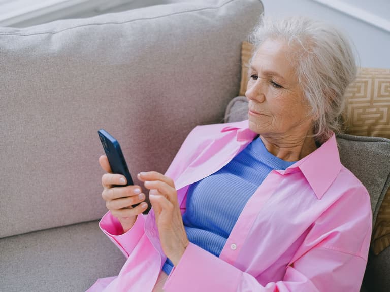 Femme âgée consultant son téléphone dans son salon