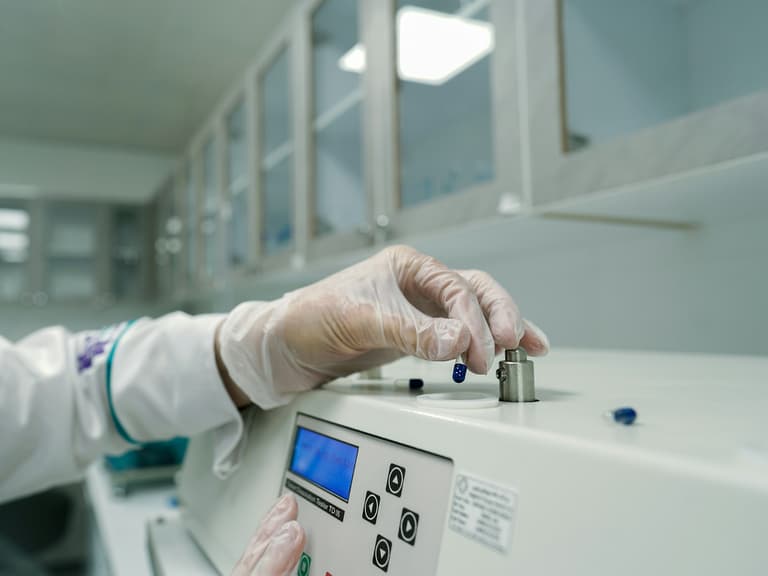 Main gantée insérant un tube d'échantillon dans un instrument de laboratoire