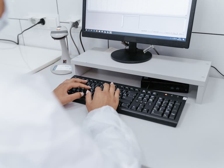 Professionnel de laboratoire saisissant des données à un poste de travail équipé d'un lecteur de codes-barres
