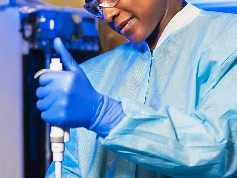 Scientifique de laboratoire en tenue de protection pipetant des échantillons