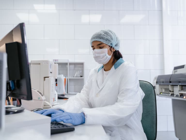 Technologue en tenue de protection travaillant à un poste informatique du laboratoire